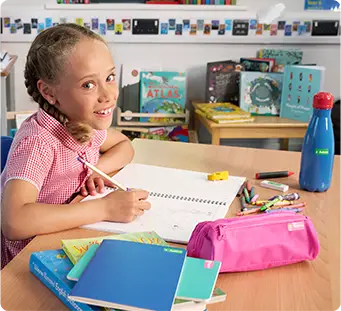 Girl at school sitting at desk writting with labelled pencil surrounded buy other labelled school items
