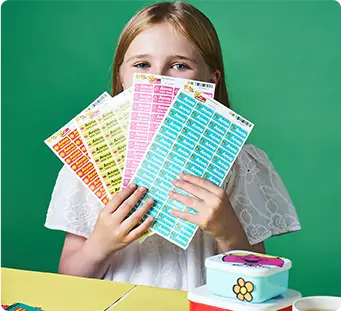 Happy girl holding up her sets of colourful sticker name labels