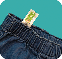 A stick-on name label applied to the washing-care label of a school jumper