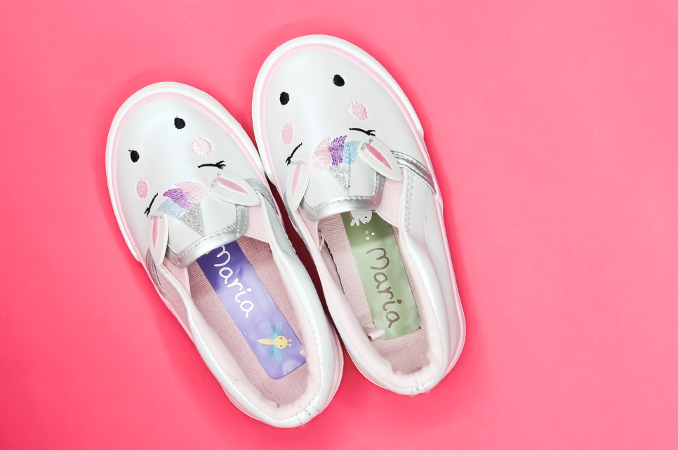 White shoes on a light green background. Inside is a name label, reading "Lucas"