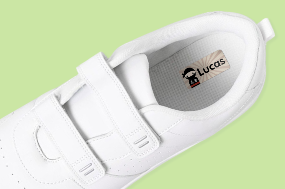 White shoes on a light green background. Inside is a name label, reading "Lucas"