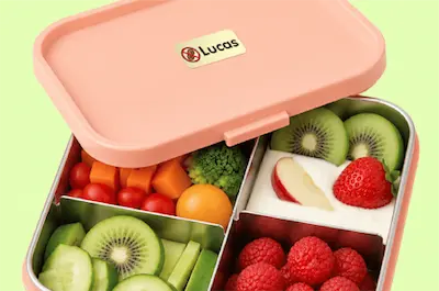 A blue lunchbox with a "Nut Allergy" name label slightly open to reveal healthy foods.