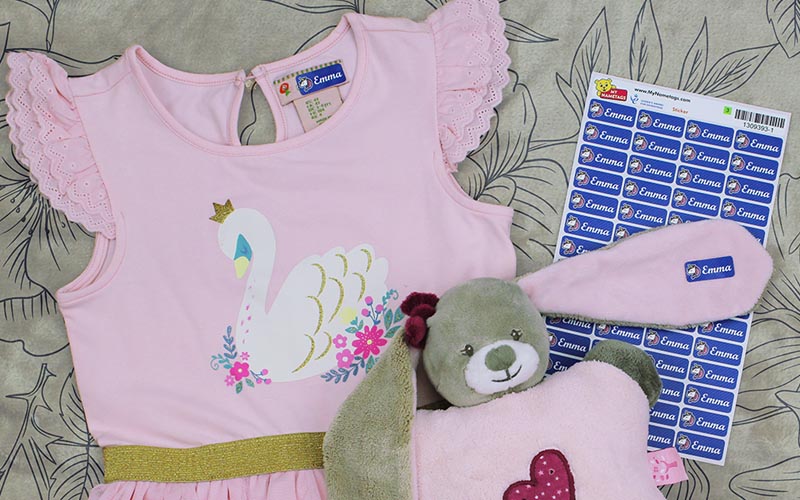 pink childrens top with My Nametags clothing name label and a teddy on a brown tablecloth with drawn flowers