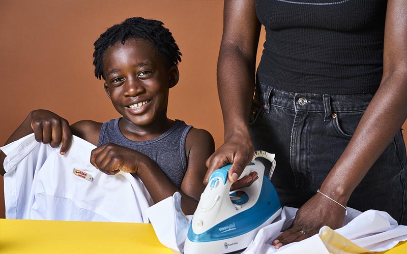 Mother and son ironing name labels onto school uniform