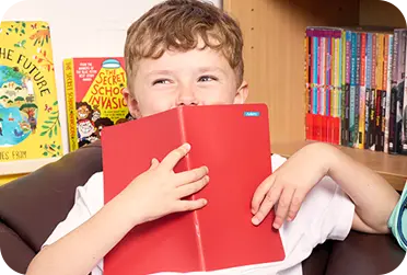 Child holding red book with ministicker on it