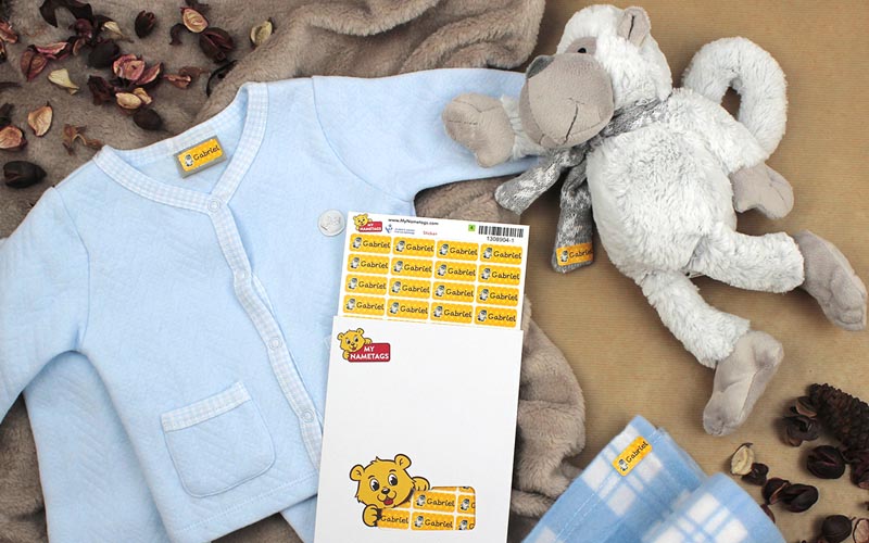name sticker for clothes on a blue kids cardigan and a soft toy, on a brown background