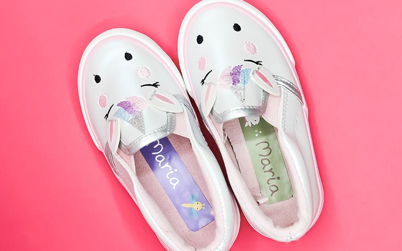 Cute white children's trainers with shoe name stickers from My Nametags on a pink backround